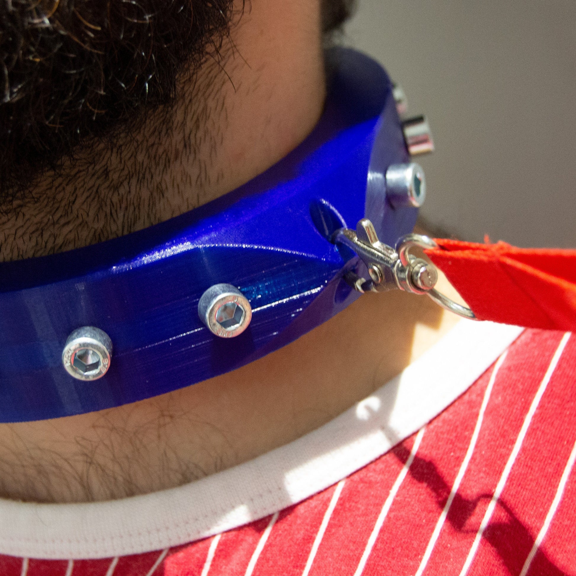 Boy wearing blue 3d printed bdsm collar adorned with bolts seen from the side